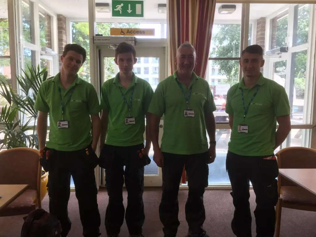 Group photo of 4 members of staff smiling in their green polos