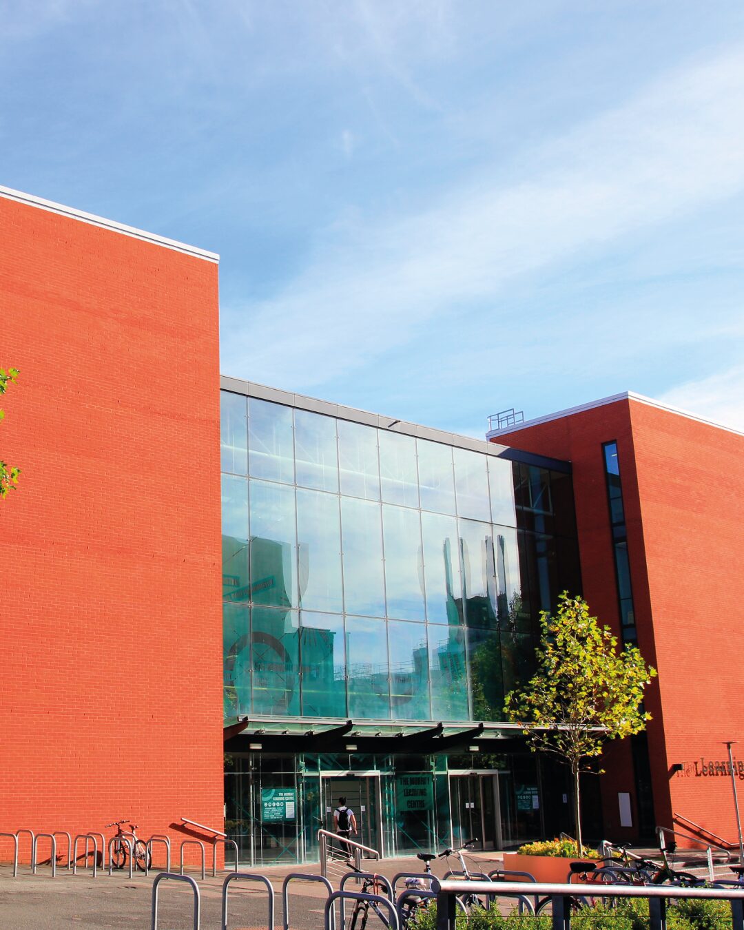 Image of the front of an orange building with big glass windows over the entrance